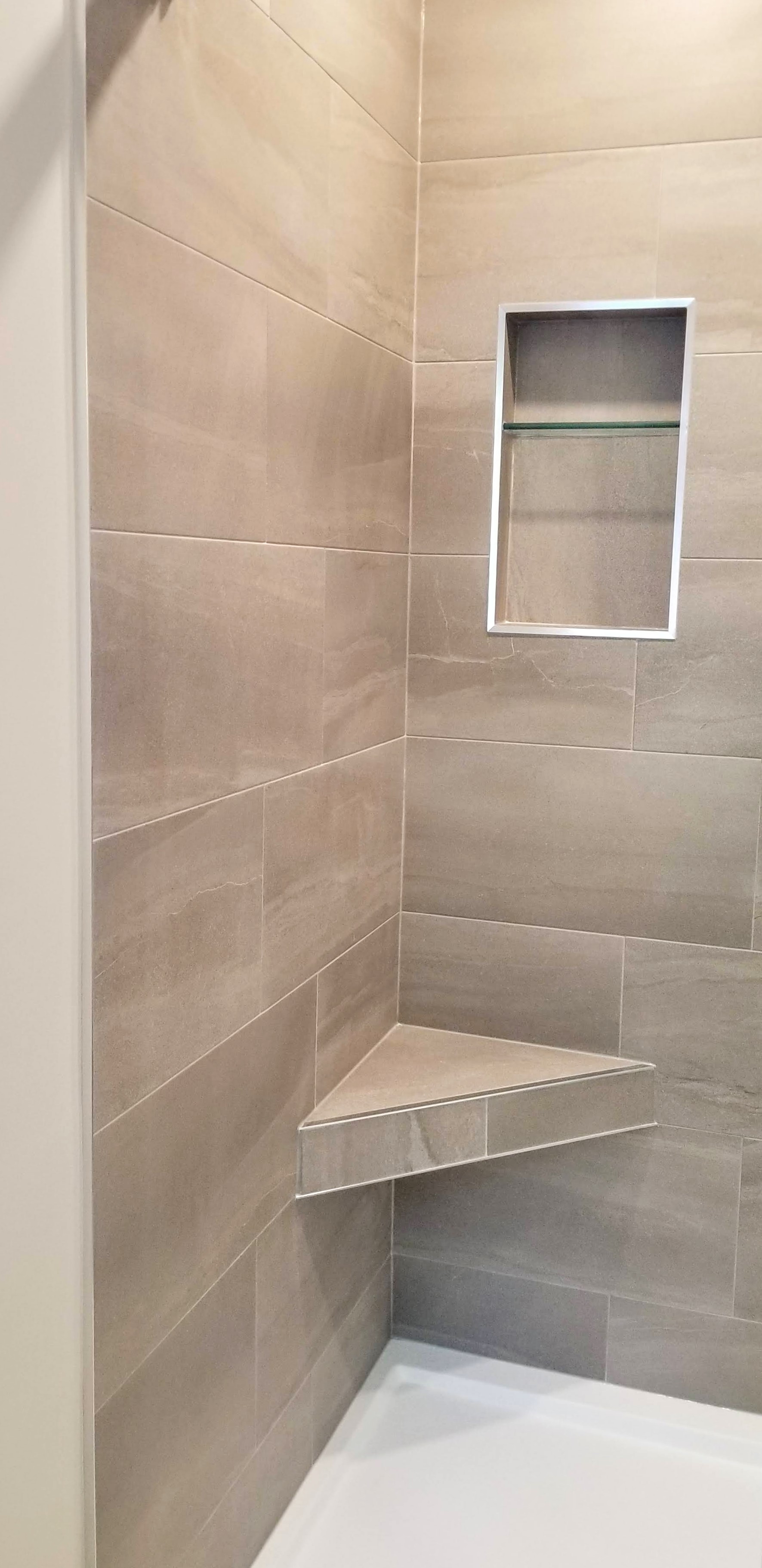 Tiled floating shower bench in tiled shower by Germano Creative Interior Contracting Ltd.