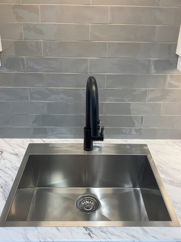 Drop in, stainless steel sink featuring a matte black faucet