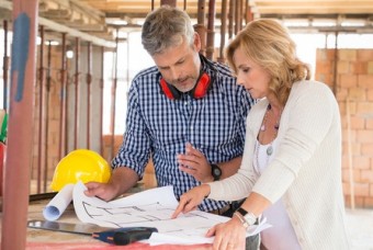 Male architect and woman discussing blueprint plan at construction site