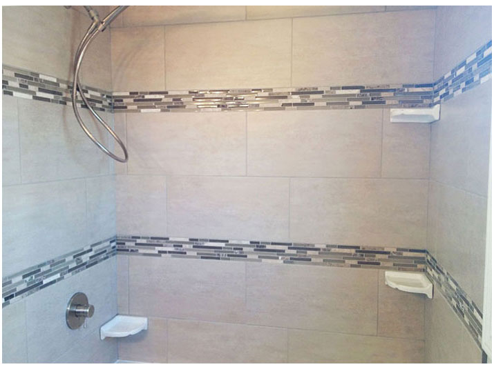 Tiled walls surround bathtub with mosaic tile accent borders