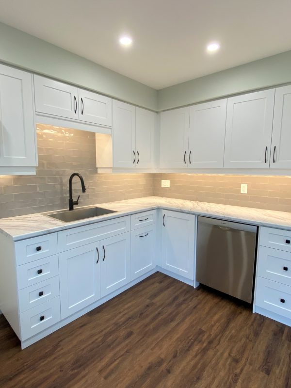 White shaker style kitchen cabinets featuring a laminate countertop