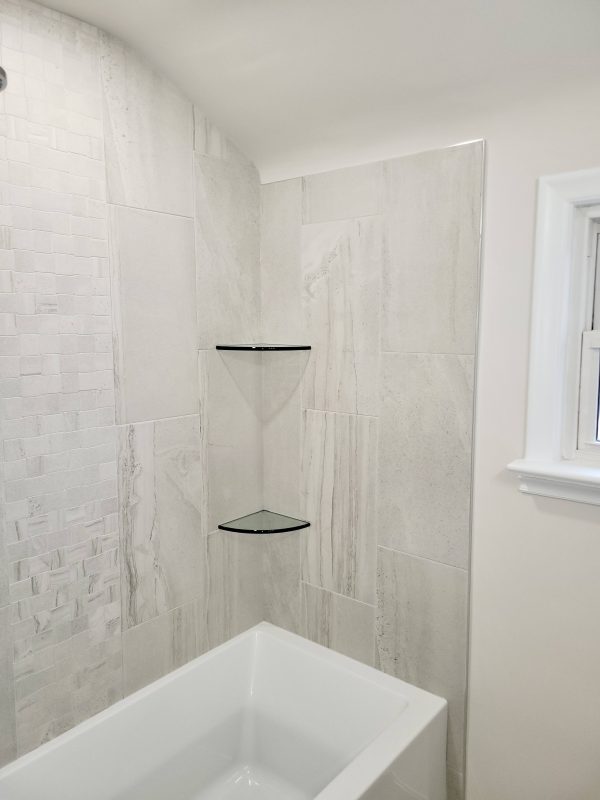 Porcelain tile shower surround featuring glass corner shelves