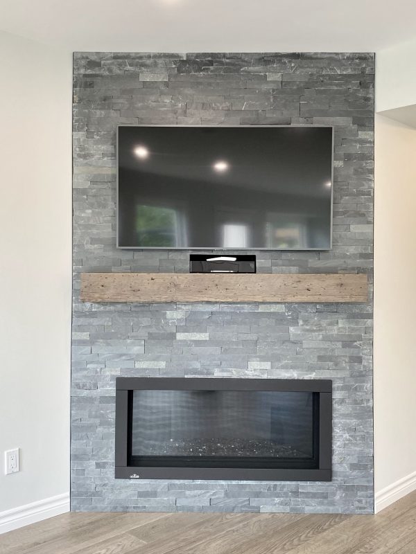 Gas fireplace featuring tile surround and barn beam mantle