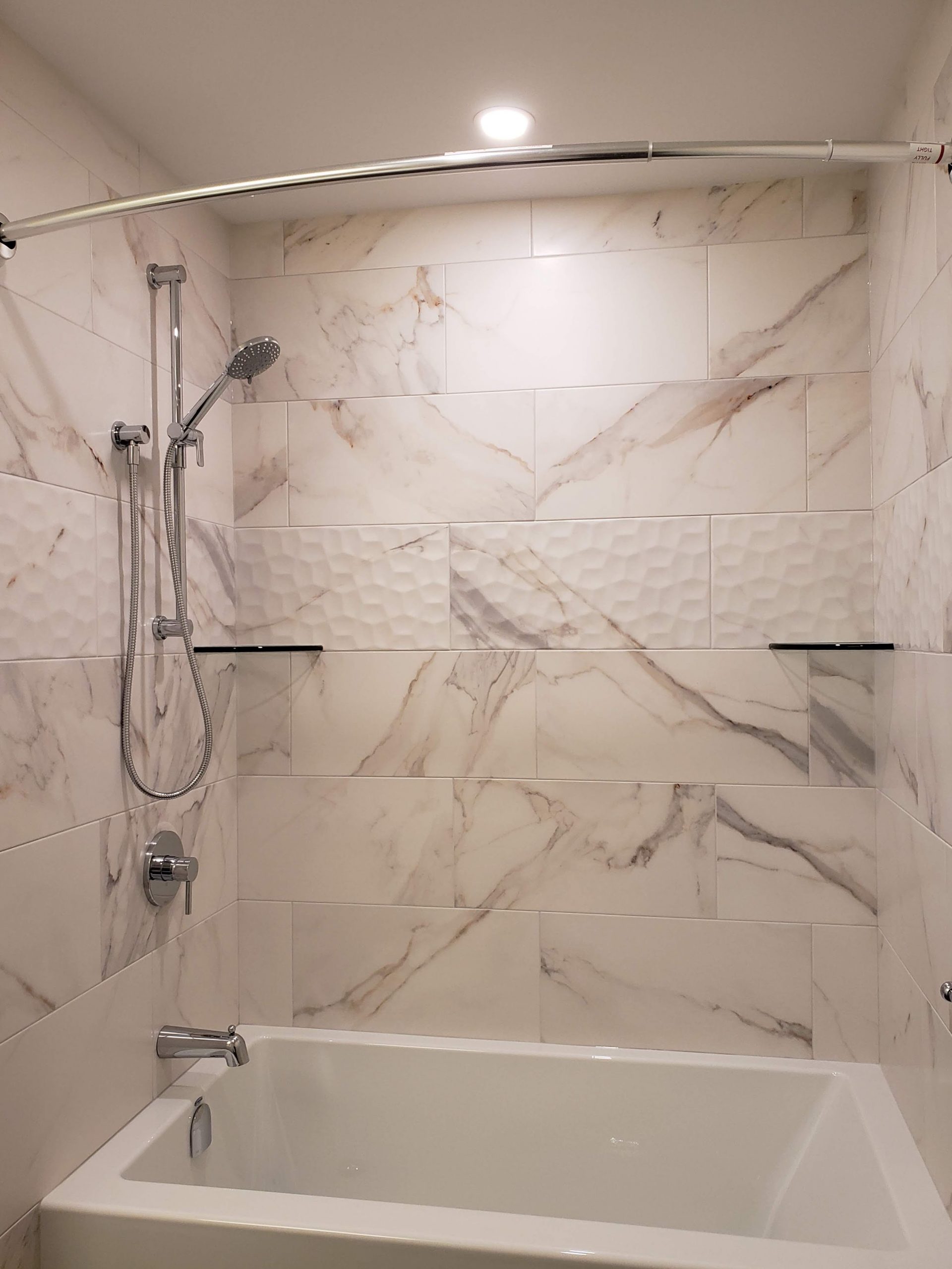 Bathtub featuring marble porcelain tile shower surround