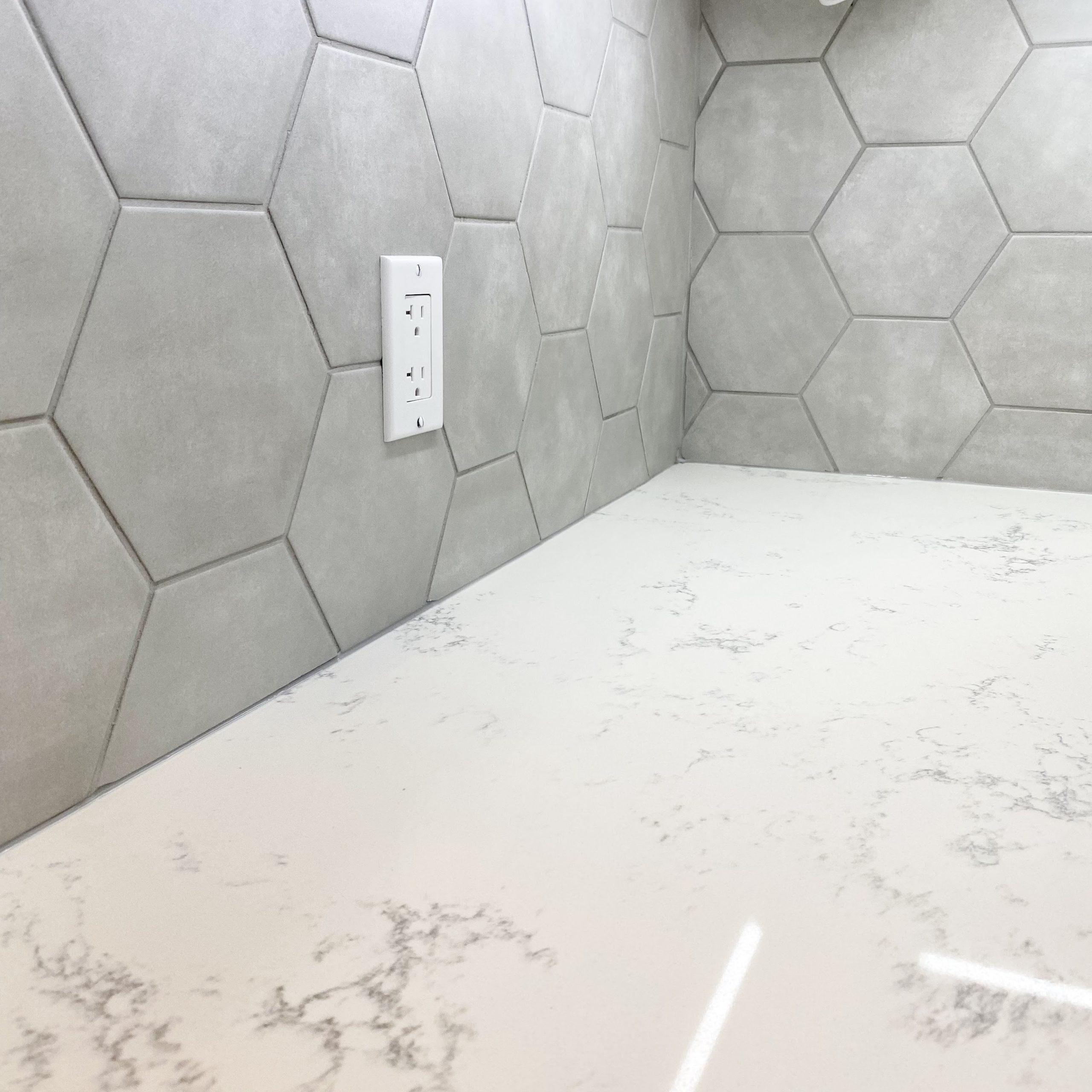 Quartz countertop featuring hexagon tile backsplash