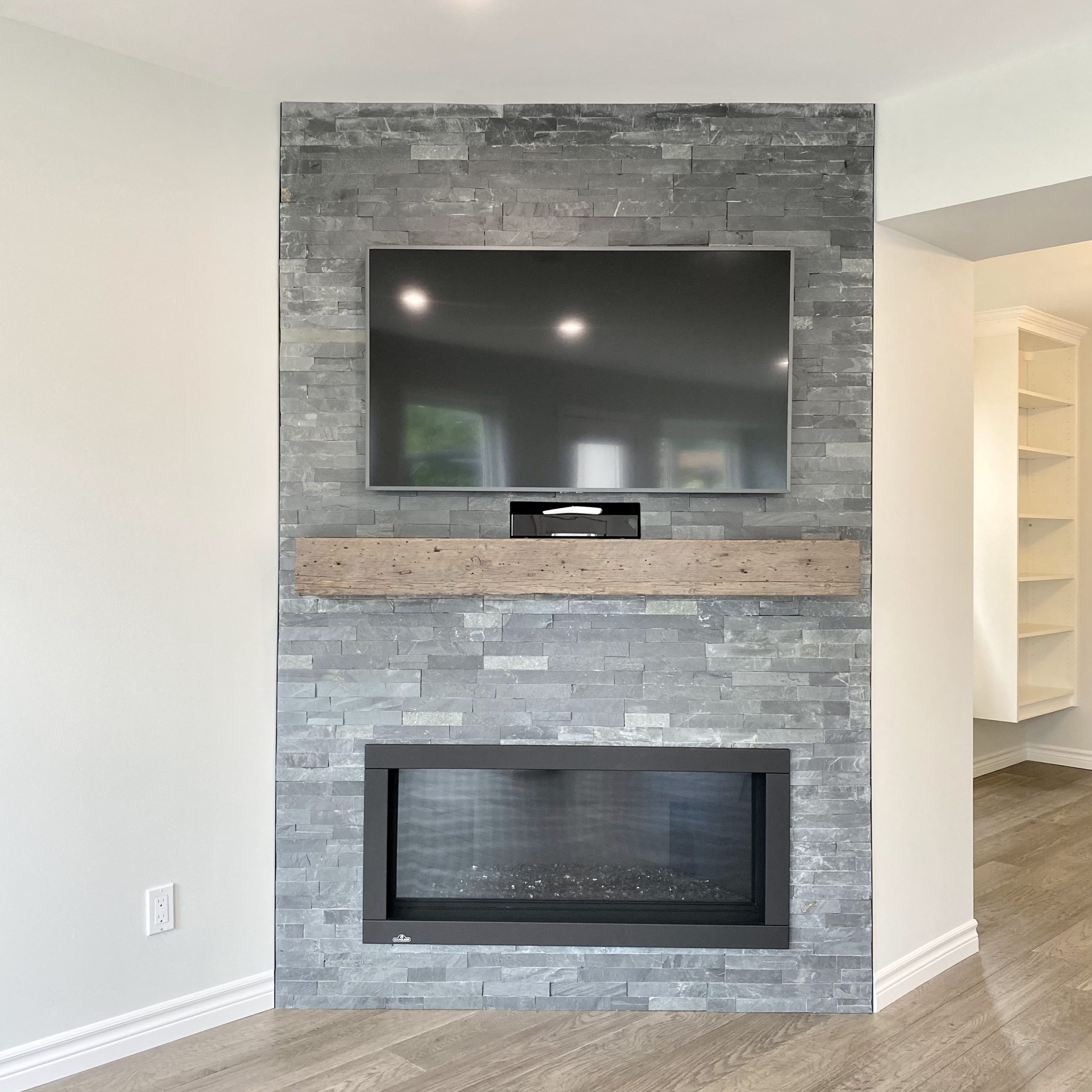 Gas fireplace featuring tile surround and barn beam mantle